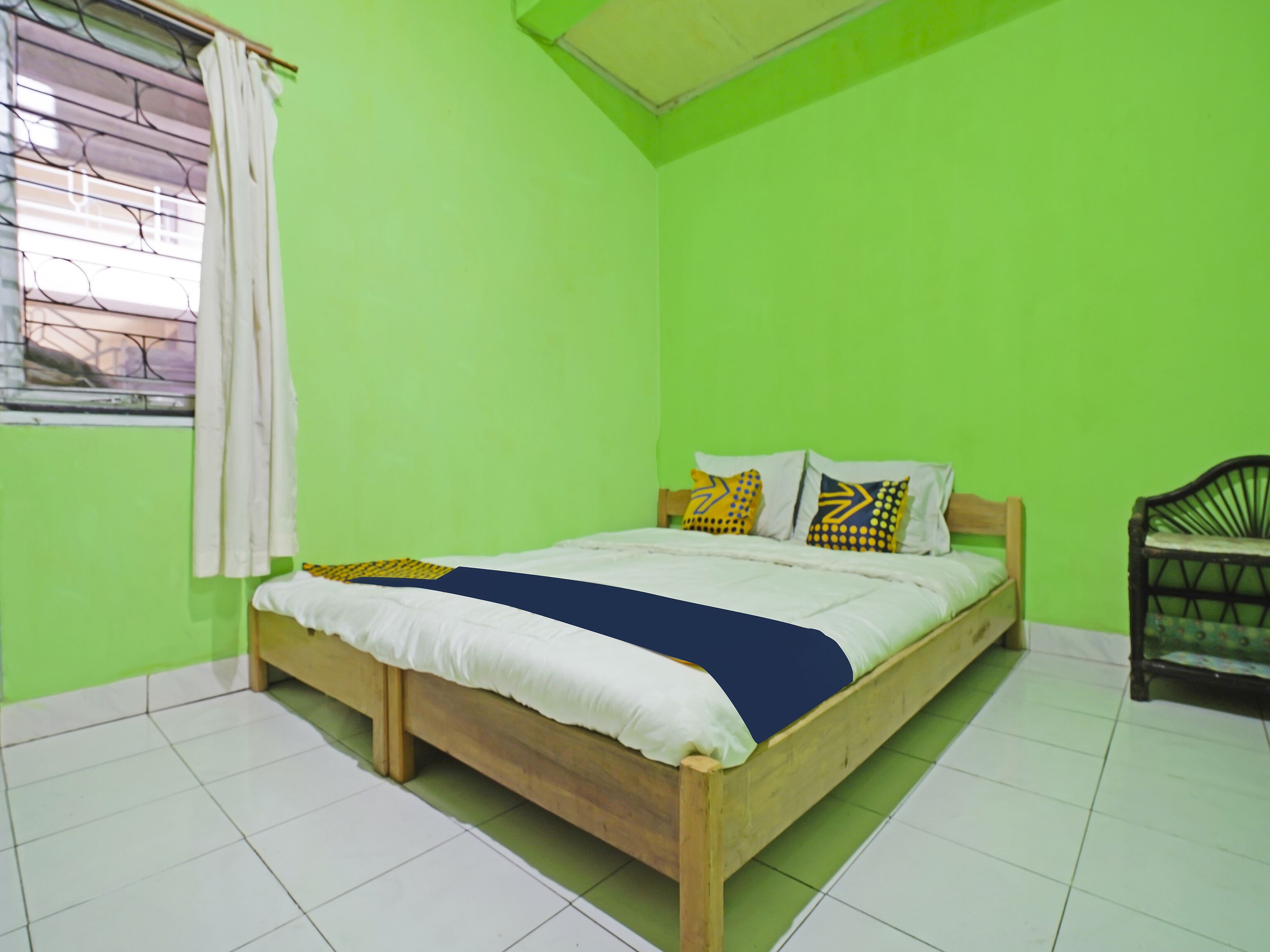 A room with a bed, a window with curtains, and a chair.
