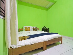 A single bed with a wooden frame, white bedding, and a blue and yellow patterned bedspread. - SPOT ON 91543 Pondok Denki 11  (Bandung)