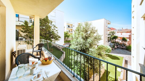 En balkon med et spisebord, stole og en kurv med frugt.