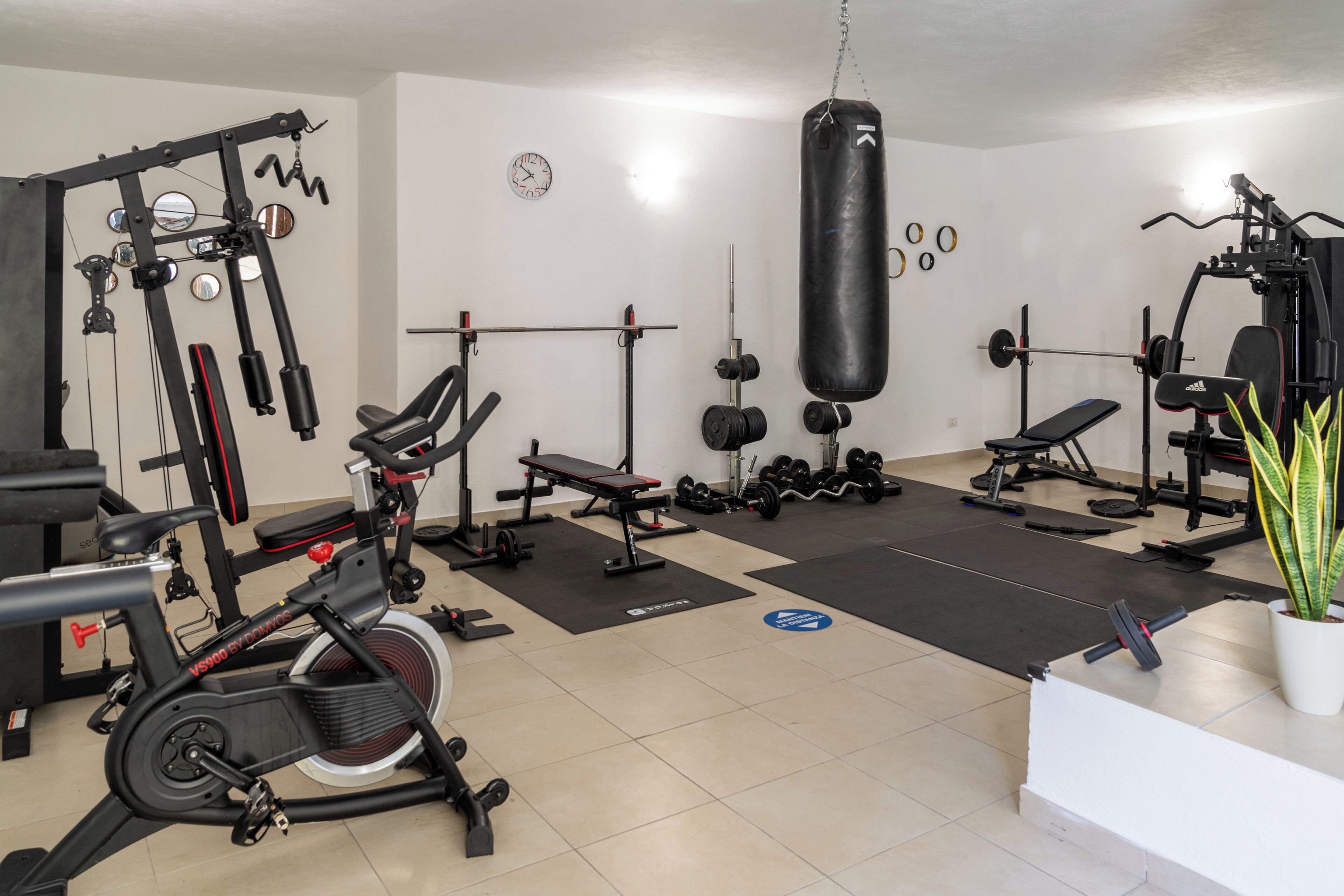A gym with exercise equipment, a punching bag, and a clock on the wall.