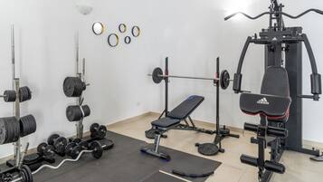 Une salle de sport équipée de matériel de musculation, d’un banc et d’un support à squats.