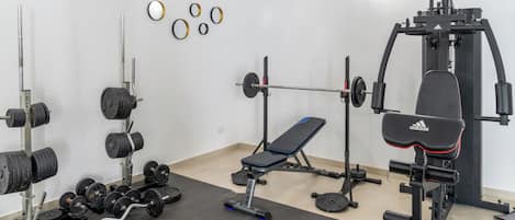 A gym with weightlifting equipment, a bench, and a squat rack.