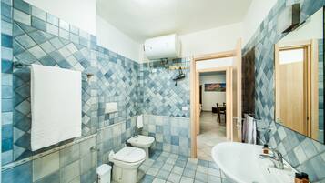 A bathroom with a blue-tiled wall, a white sink, and two toilets.