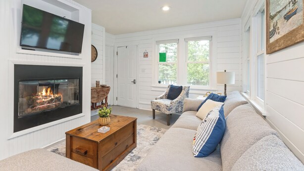 A living room with a fireplace, a television, a sofa, and a chair.