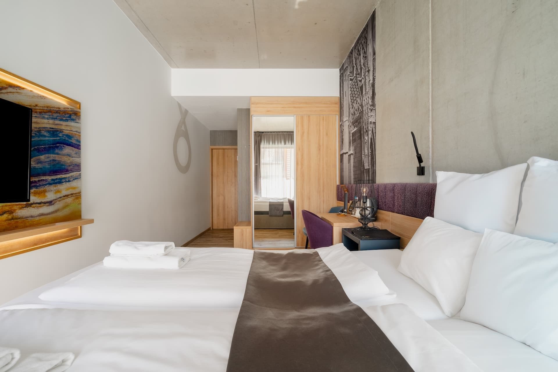 Una habitación de hotel con una cama, un escritorio, una silla y un televisor.