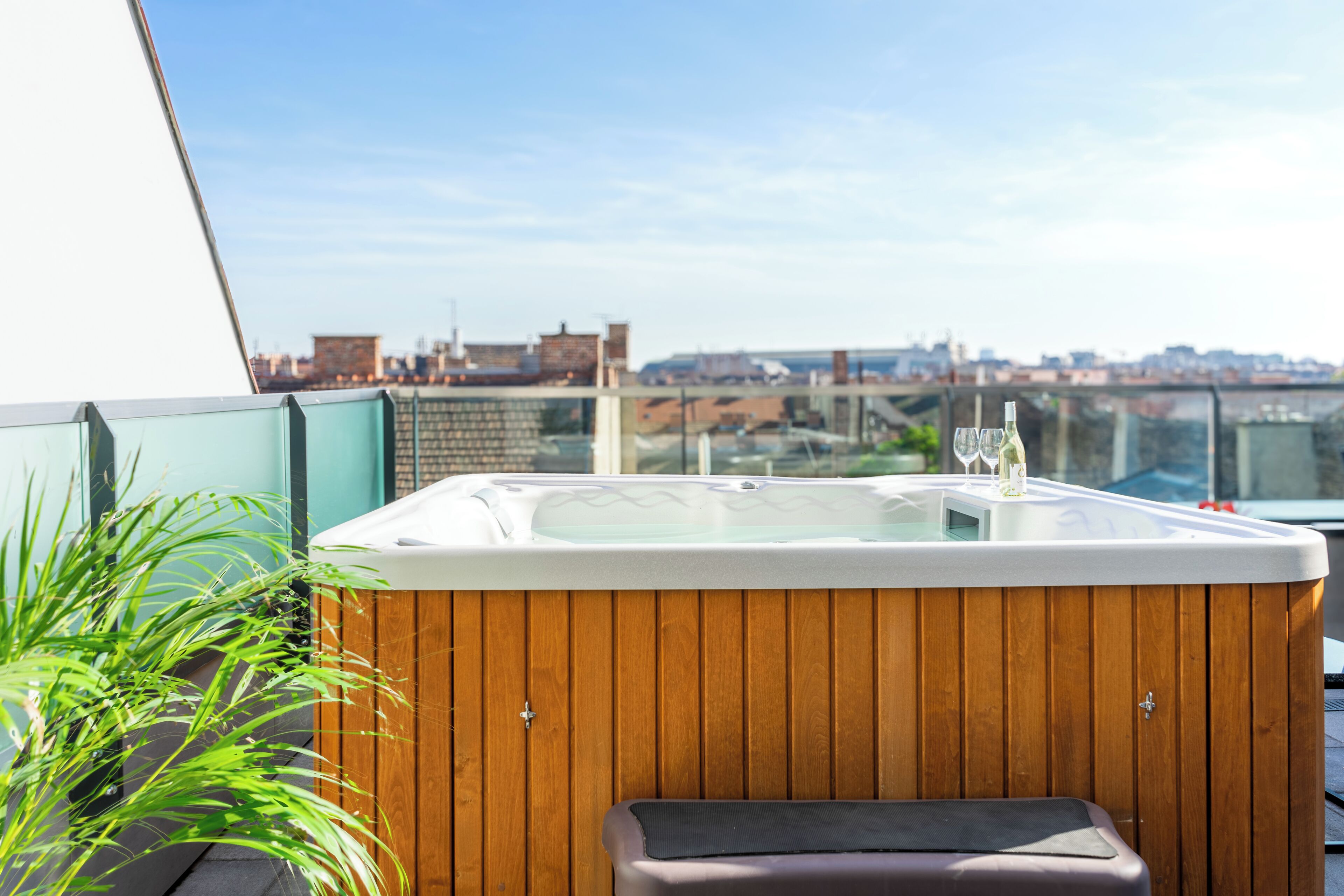Un bain à remous avec une structure extérieure en bois, un banc et une paroi en verre.