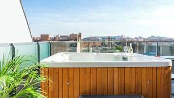 Un bain à remous avec une structure extérieure en bois, un banc et une paroi en verre.