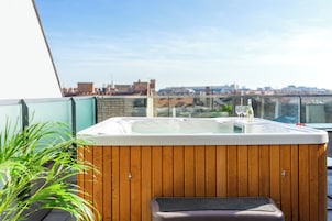 Un jacuzzi con revestimiento de madera, un banco y un cerramiento de vidrio.