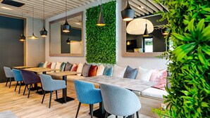 A modern restaurant interior with wooden tables and chairs, a green wall, and pendant lighting. - Onyx Luxury Budapest (Budapest)