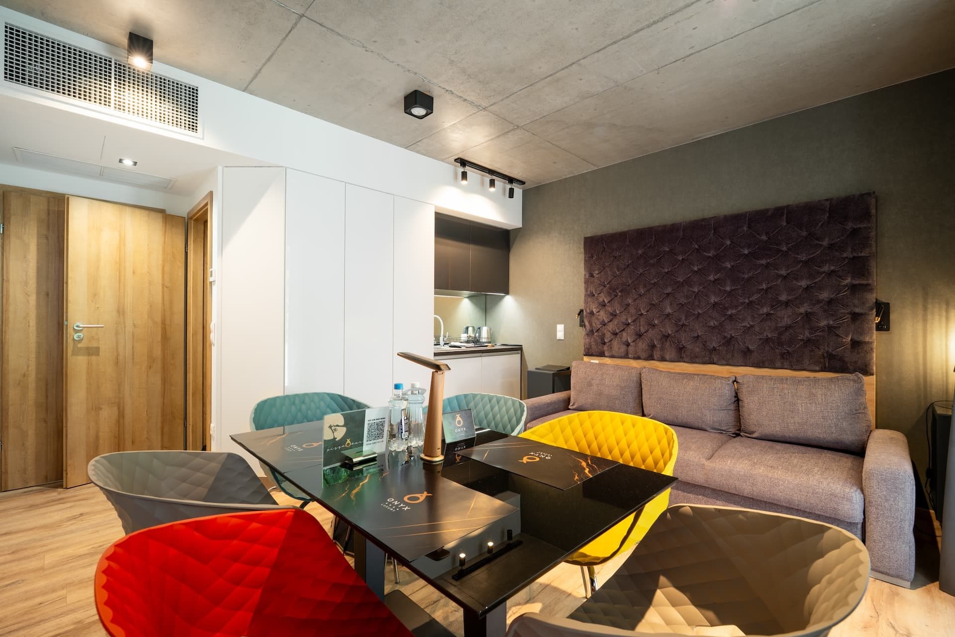 Una sala de estar moderna con un sofá, una mesa de comedor y sillas. Se observa un área de cocina al fondo.
