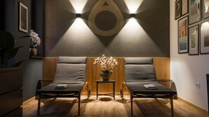 A room with two reclining chairs, a small table with a flower vase, and framed pictures on the wall. - Onyx Luxury Budapest (Budapest)