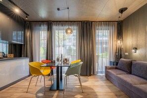A modern living room with a dining area, featuring a sofa, a dining table with chairs, and a kitchen area with a coffee machine. - Onyx Luxury Budapest (Budapest)