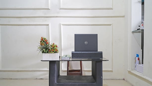 A small, dark-colored desk with a laptop and a potted plant. - SPOT ON 91545 Pondok Mukti Syariah (Bandung)