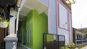 A two-story building with a green and white facade, a black metal fence, and a covered porch area. - SPOT ON 91545 Pondok Mukti Syariah (Bandung)