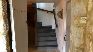 A stone-walled hallway leading to a staircase with a wooden handrail.