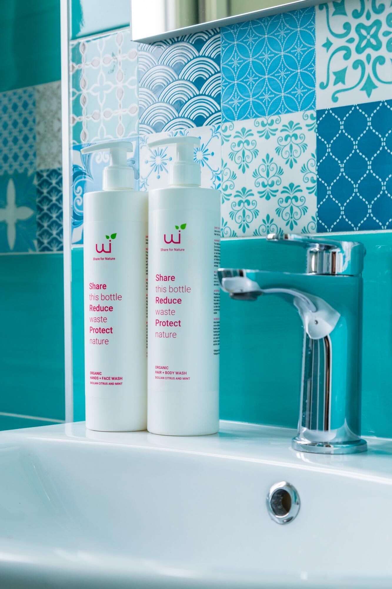 Two bottles of organic hair and body wash on a bathroom sink with a chrome faucet.
