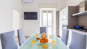 Une cuisine moderne avec un coin repas, comprenant un téléviseur, une grande fenêtre et divers appareils électroménagers.