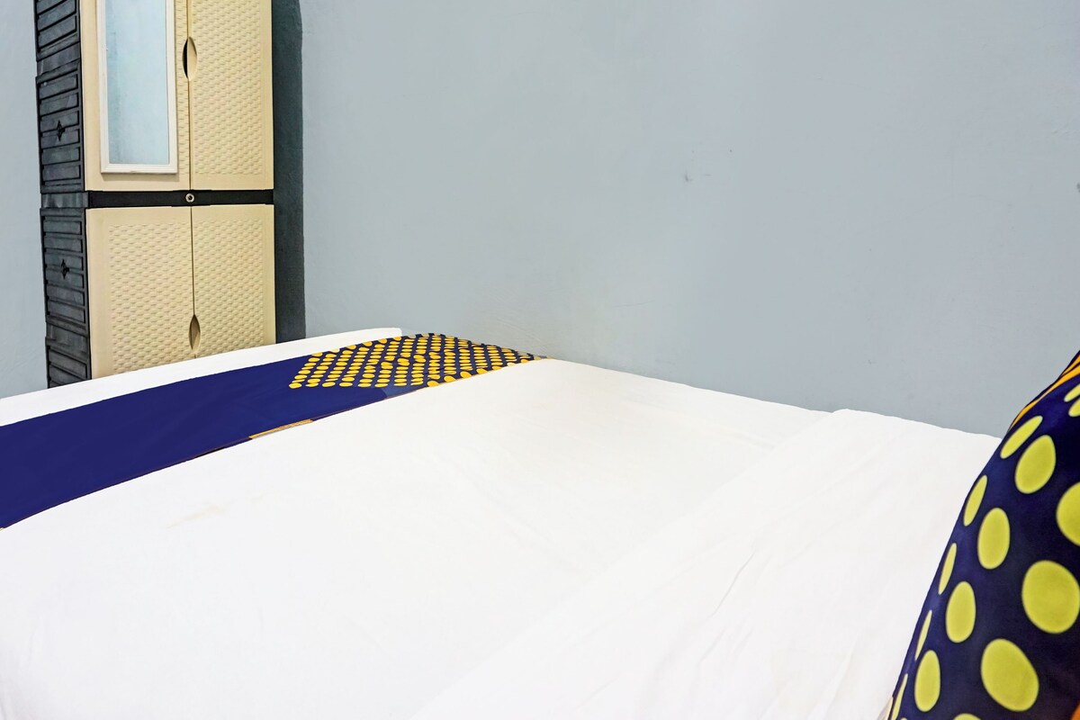 A bed with a patterned bedspread, a wardrobe, and a plain wall.