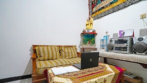 A room with a wooden sofa, a laptop on a patterned table, a fish tank, and speakers on a shelf. - SPOT ON 91723 Sony Homestay Syariah (Sukabumi)