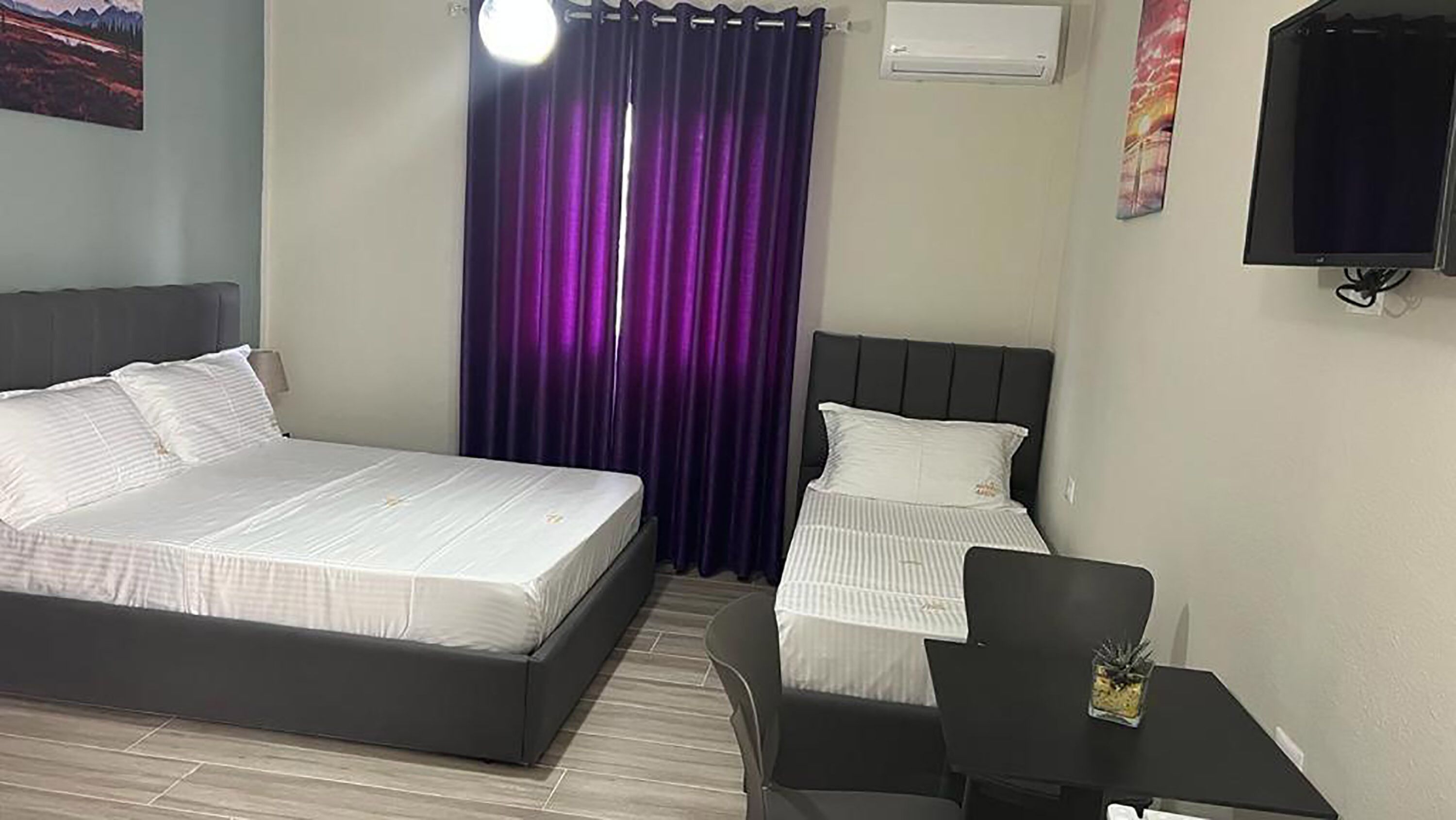 Una habitación de hotel con una cama grande, una cama más pequeña, un escritorio y una silla.