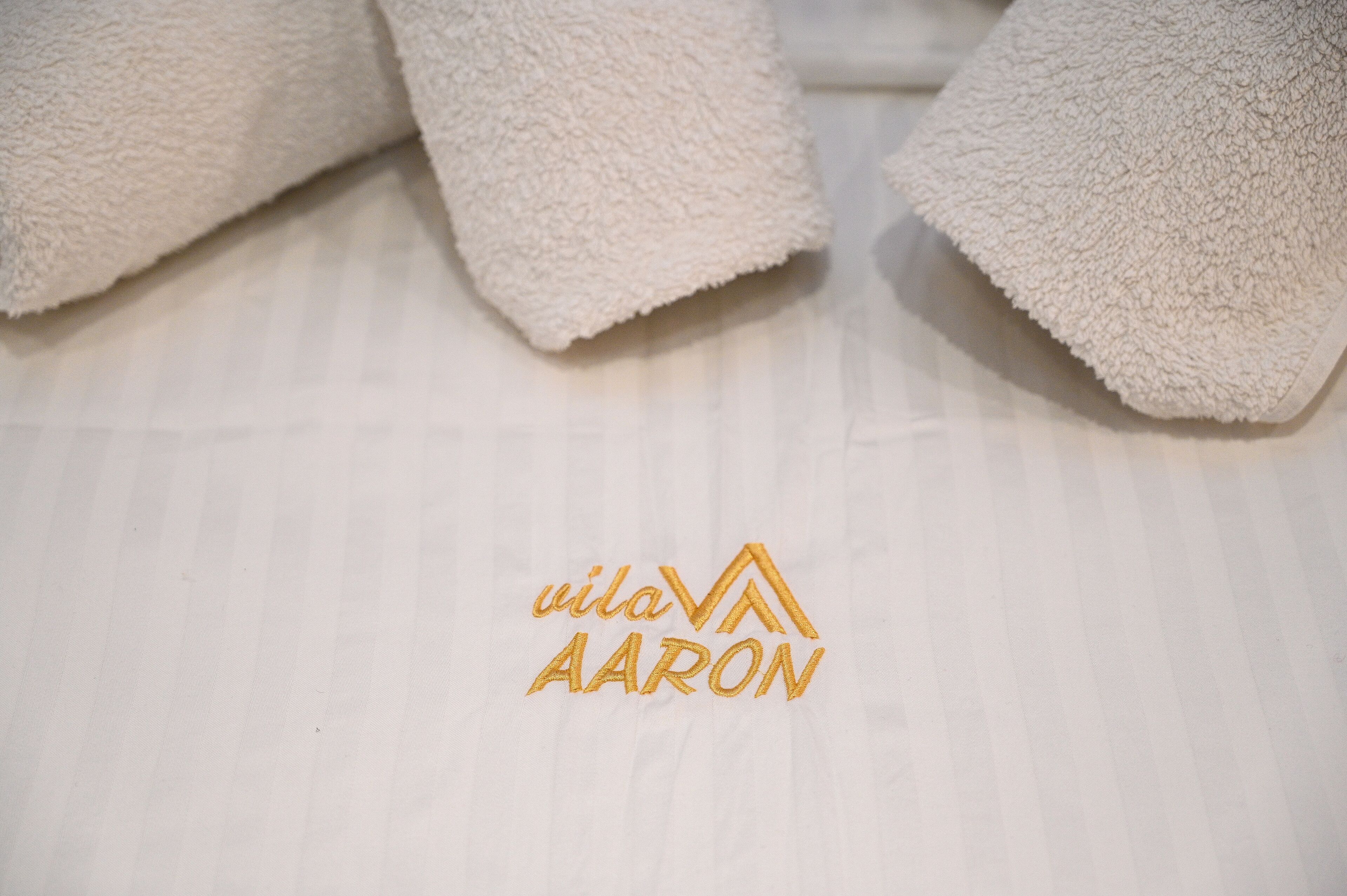 En vit, strukturerad yta med en logotyp som visar texten ”vila AARON”.