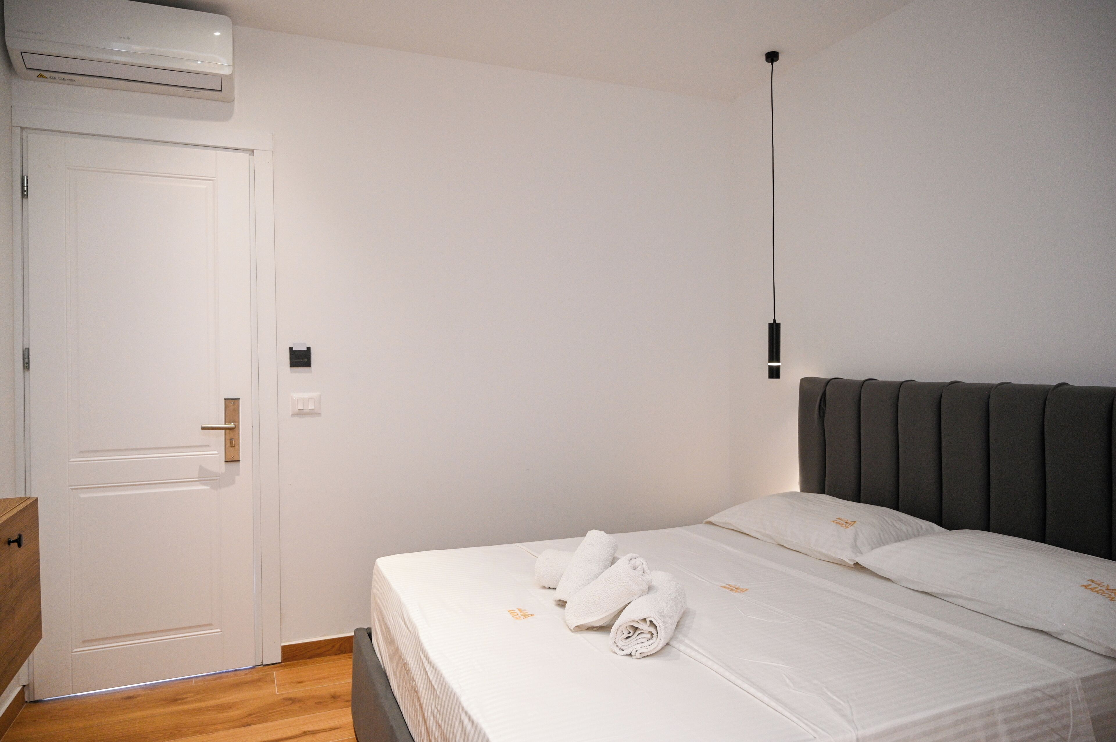 A hotel room with a bed, a door, and an air conditioning unit.