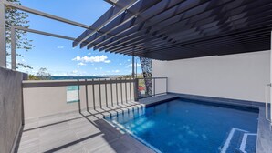 A modern outdoor swimming pool with a clear view of the sea and a pergola structure.