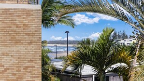 A beachfront view with a clear sky, palm trees, and a brick building.