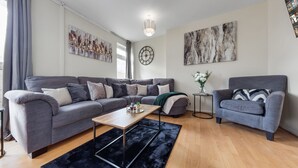 A modern living room with a grey sofa, a matching armchair, a coffee table, and a black rug.