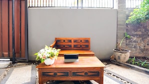 A wooden bench with a potted plant and a tablet on a table. - OYO 91827 Tutus Homestay Syariah (Pasuruan)