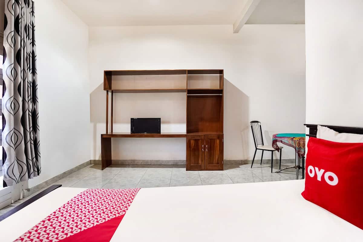 Ein Hotelzimmer mit einem Bett, einem Holzschrank, einem Schreibtisch und einem Stuhl.