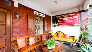 A traditional wooden bench and sofa set with a potted plant, a wooden table, and a wall-mounted lamp. - OYO 91827 Tutus Homestay Syariah (Pasuruan)