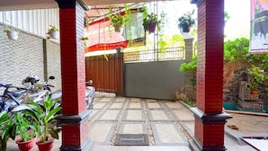 A covered entrance with a tiled floor, potted plants, and a red brick pillar. - OYO 91827 Tutus Homestay Syariah (Pasuruan)