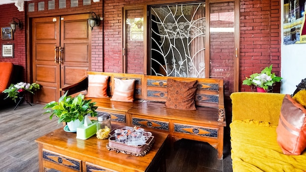A traditional room with a wooden bench, a table with a vase and a tray, and a yellow armchair. - OYO 91827 Tutus Homestay Syariah (Pasuruan)
