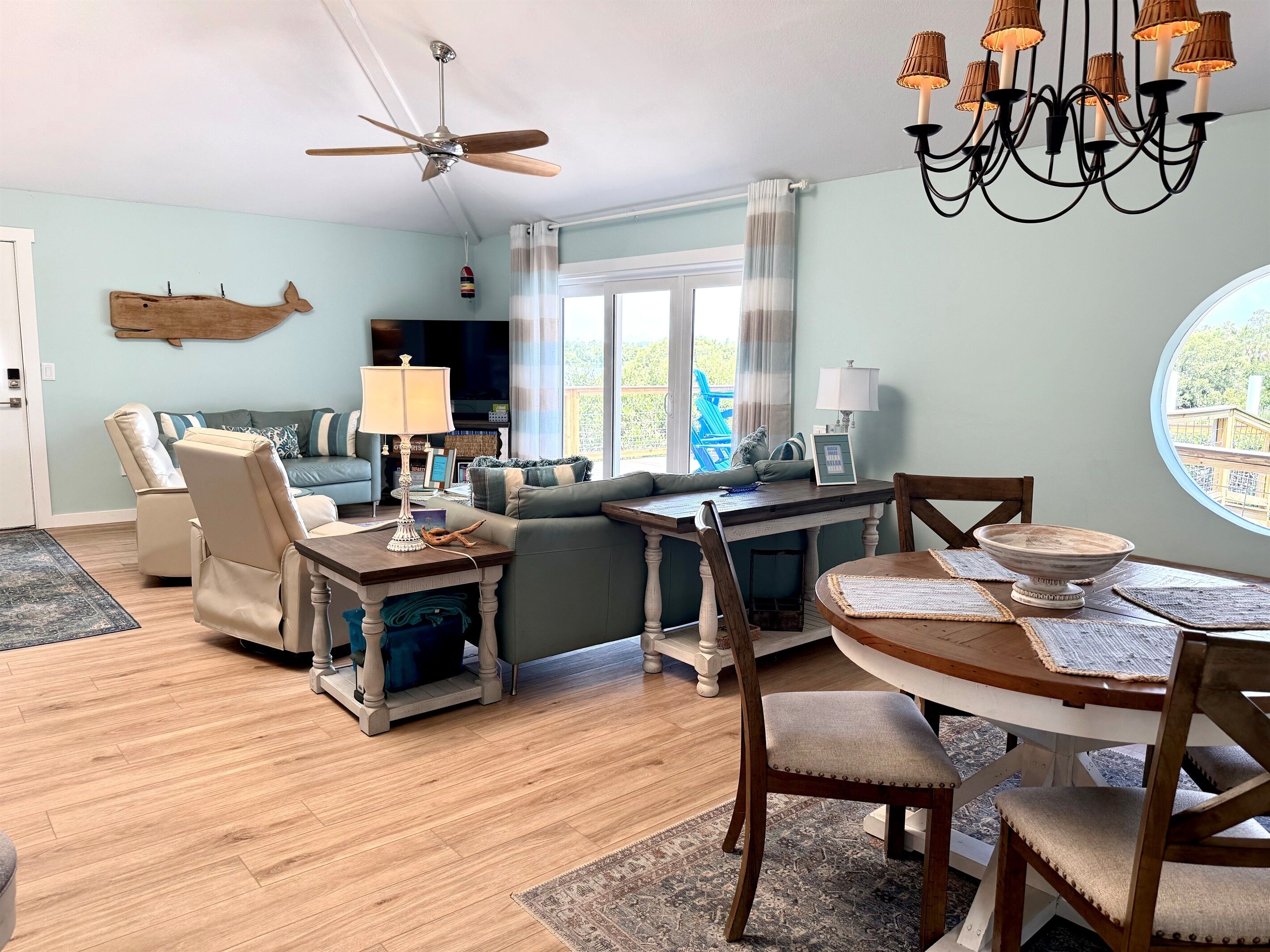Un salon comprenant un canapé, des fauteuils, une table à manger, un lustre et un ventilateur de plafond.