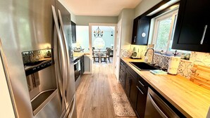 A modern kitchen with stainless steel appliances, wooden countertops, and a dining area with a chandelier.