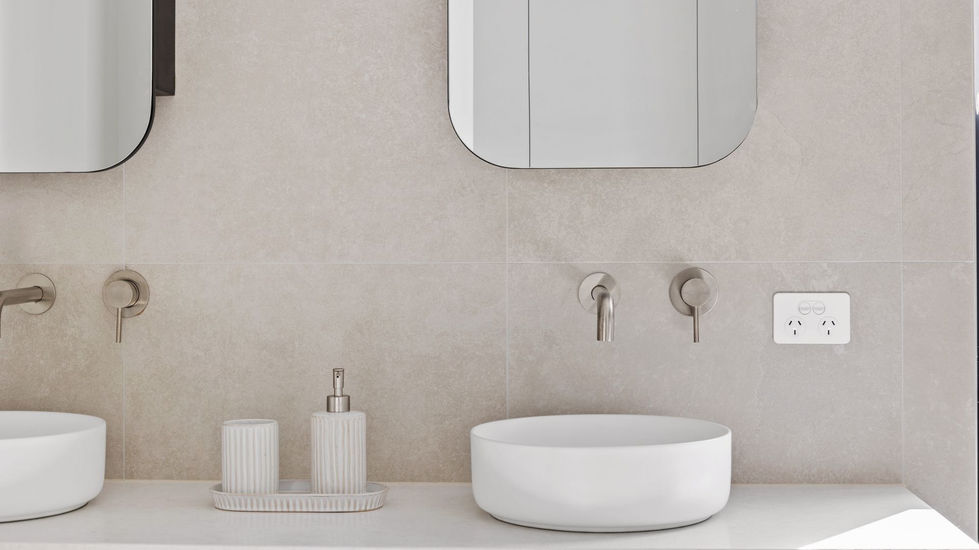 A modern bathroom with two sinks, a mirror, and a towel rack.