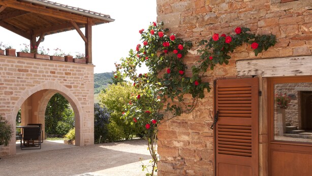 Un edificio de piedra con puerta de madera y un patio cubierto.