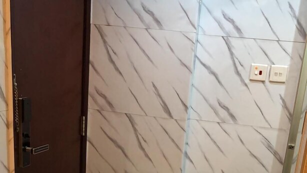 Une chambre d’hôtel avec un mur décoré d’un motif imitant le marbre, une porte en bois et un lit doté d’une tête de lit en bois.