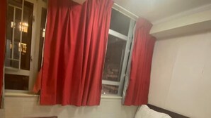 Une chambre d’hôtel avec un lit, une table de chevet, une fenêtre avec des rideaux rouges et un escalier.