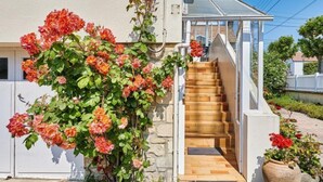 A staircase leading to a house with a white exterior and a garden with red flowers. - Janomaine by Interhome (Cabourg)