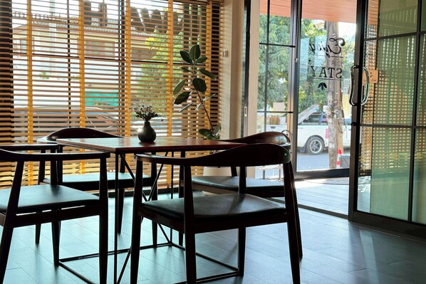 A restaurant interior with wooden blinds, a potted plant, and a view of the street outside. - Tanwa Hotel (Chiang Mai)