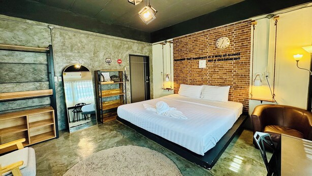 Une chambre d’hôtel moderne avec un grand lit, un mur décoratif en briques, une horloge et un bureau avec une chaise.
