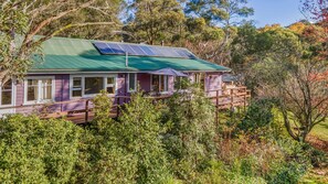Une maison dotée d’un toit végétalisé, de panneaux solaires et d’une terrasse en bois.