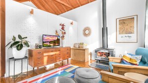 A cozy living room with a fireplace, wooden furniture, a TV, and a colorful rug. - Cooee Cottage @ Blackheath (Blackheath)