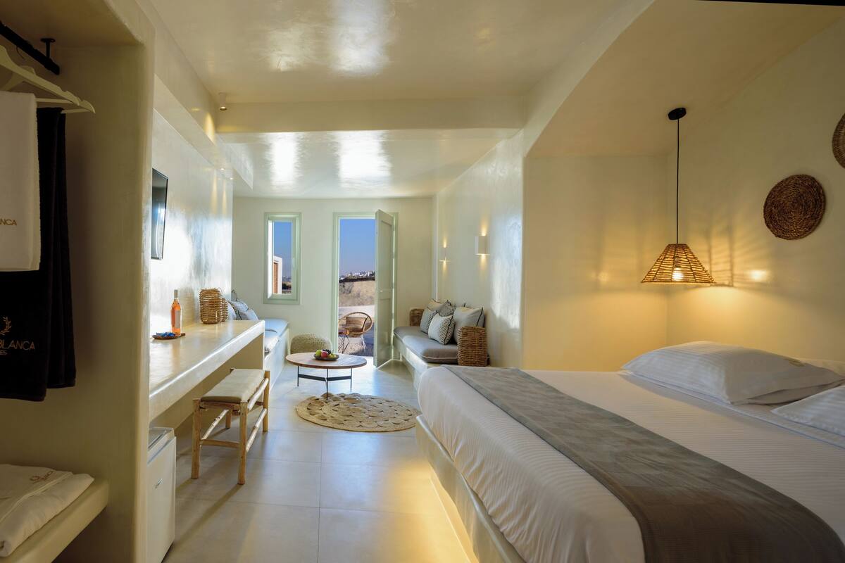 Habitación de hotel con cama, un banco, una mesa y una toalla colgada.