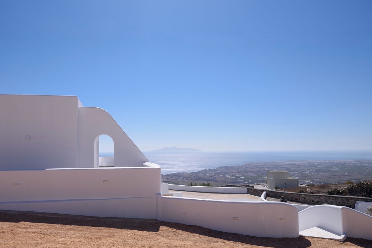 A white building with a curved balcony overlooking a coastal landscape.
