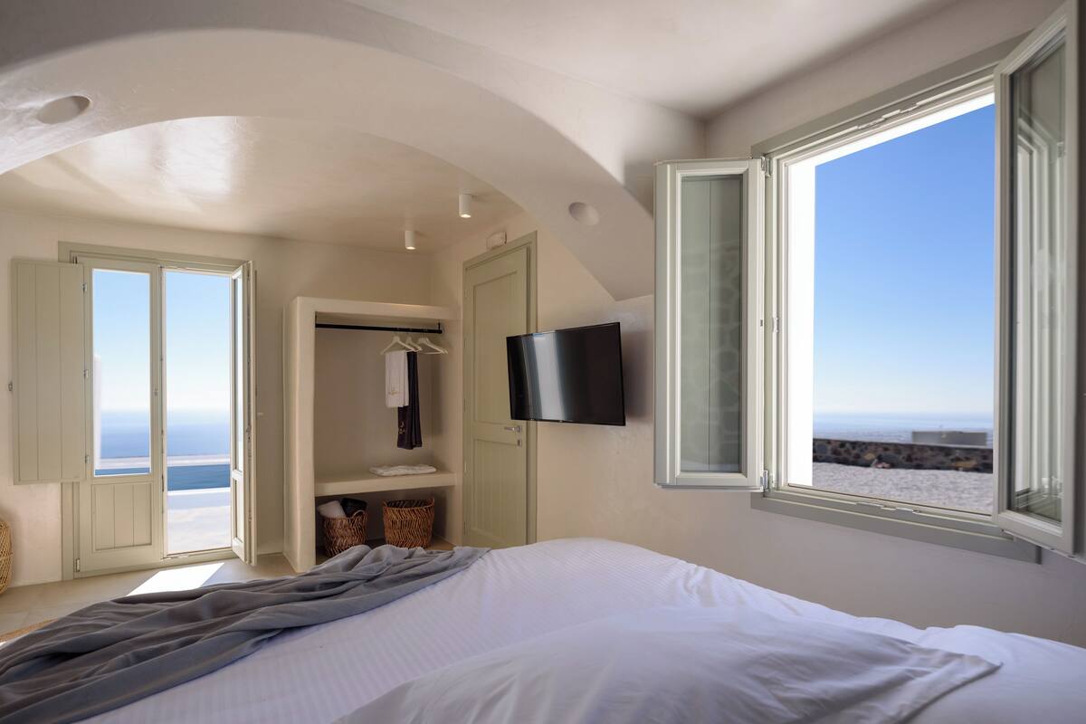 Un dormitorio con cama, televisión y vista al océano.