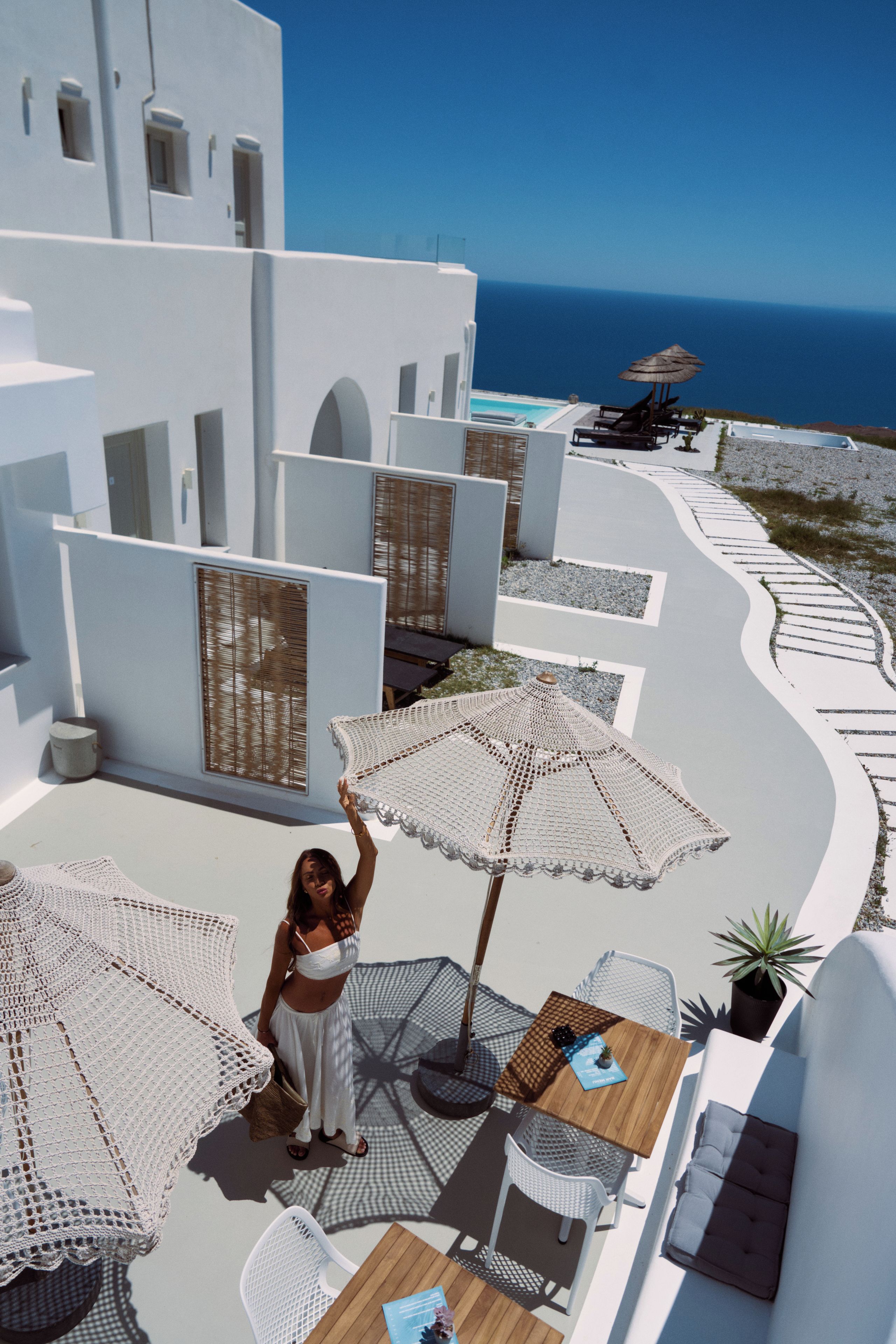 Una terraza de arquitectura blanca, con mobiliario exterior y vistas al mar.