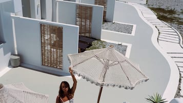 Una terraza de arquitectura blanca, con mobiliario exterior y vistas al mar.